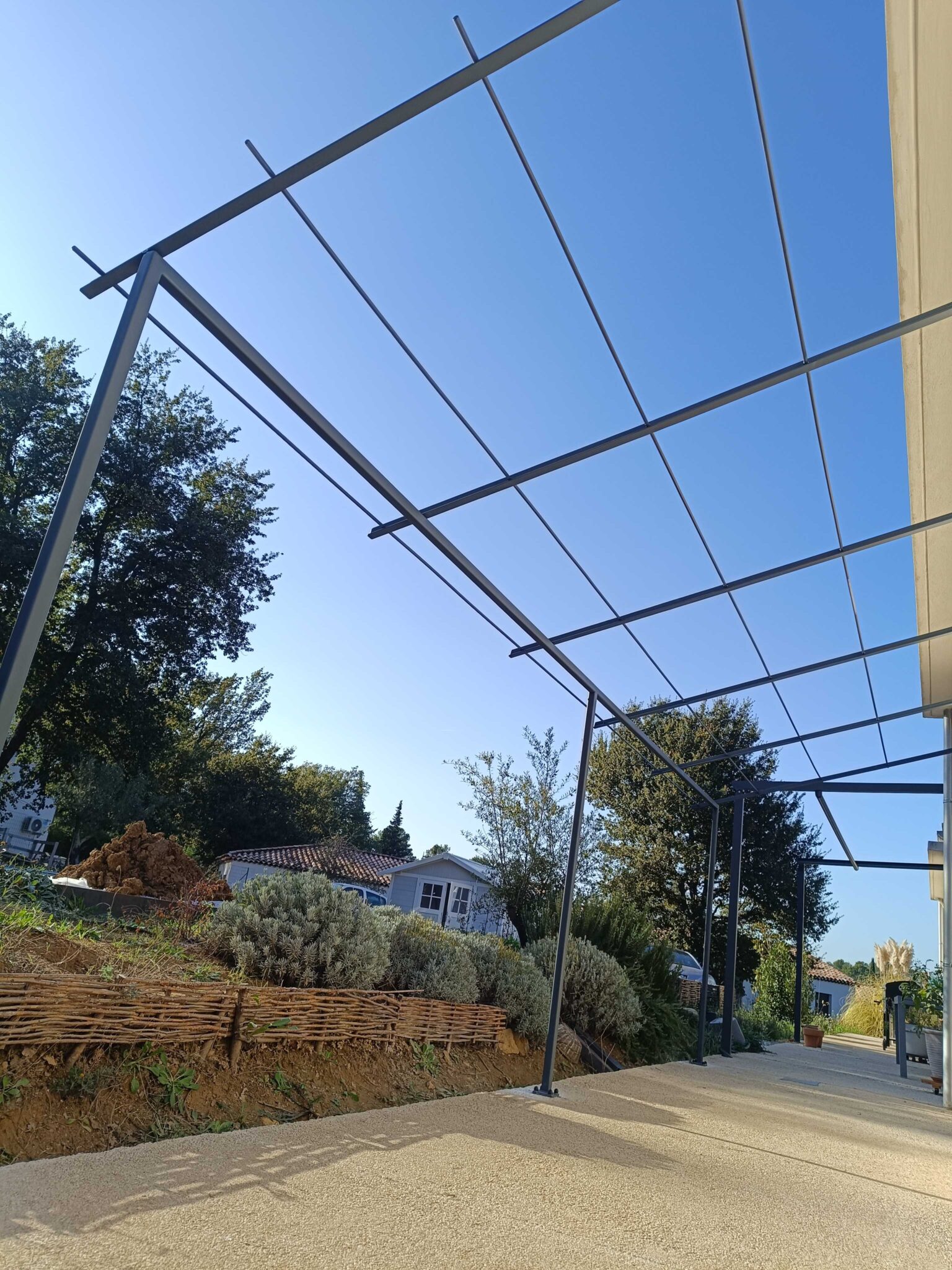 Structure de pergola contemporaine en acier – vue sur terrasse avec végétation