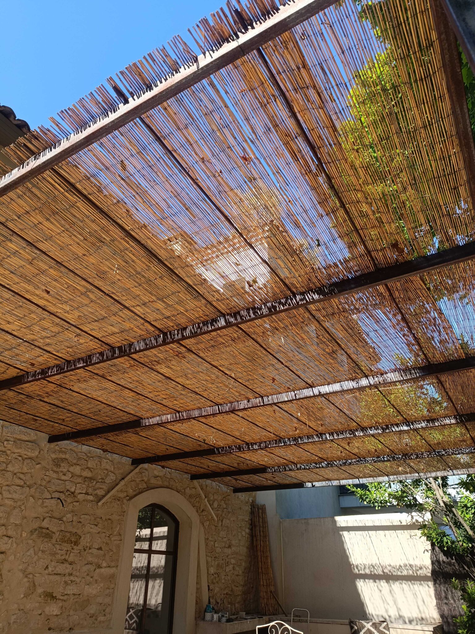 Toiture de pergola en canisses naturelles fixée sur structure en fer – vue intérieure