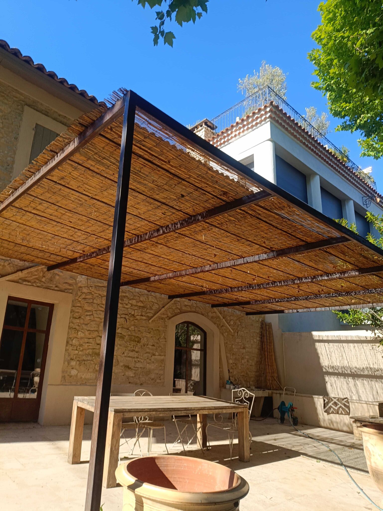 Structure métallique avec couverture en canisses – ombrage naturel sur terrasse en pierre