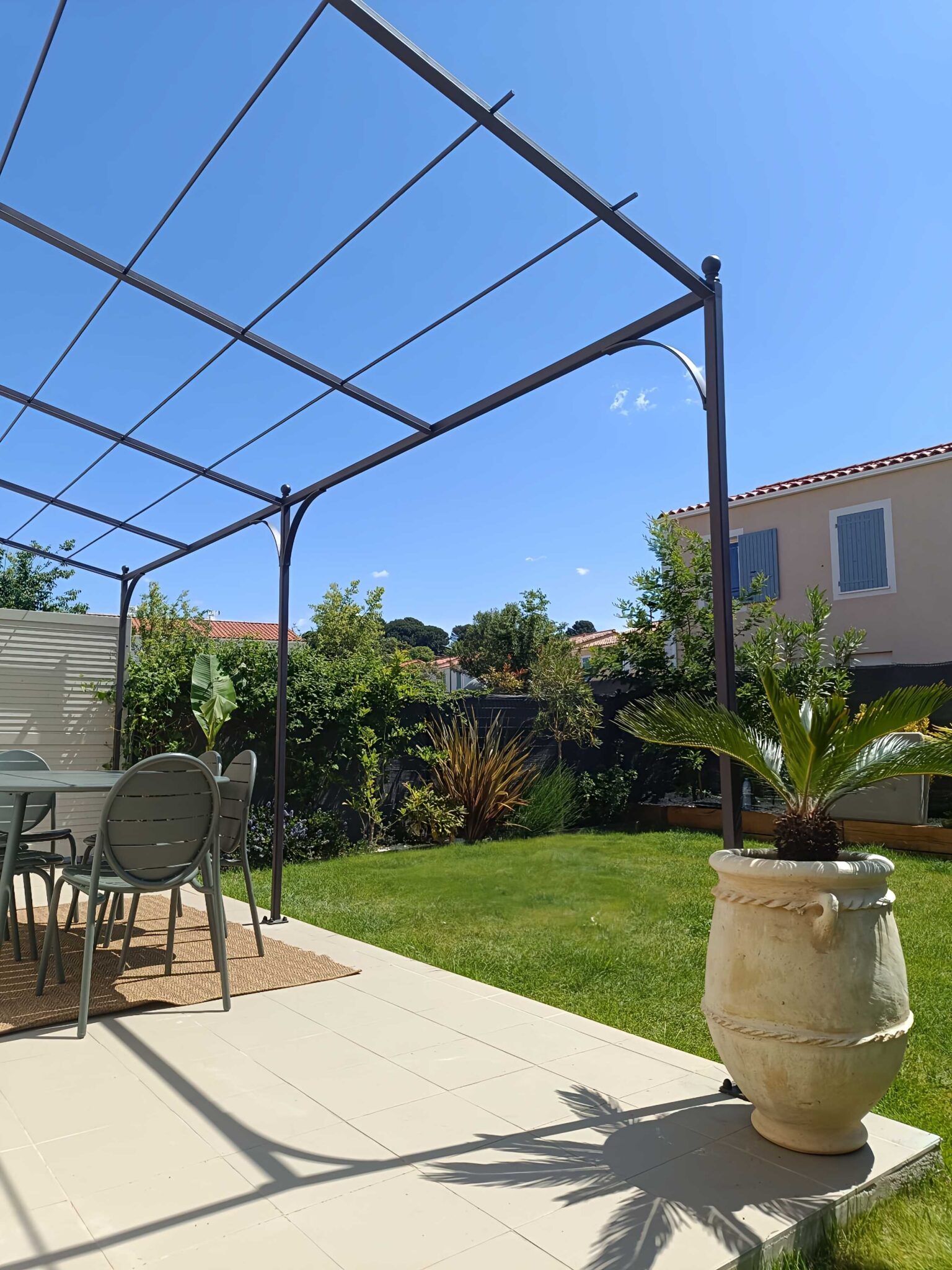 Pergola sur mesure avec arches fixée à une façade moderne – pose dans jardin résidentiel