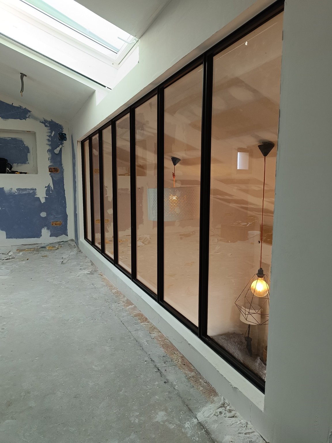 Grande verrière atelier en acier avec vitrage, séparant les espaces tout en laissant passer la lumière