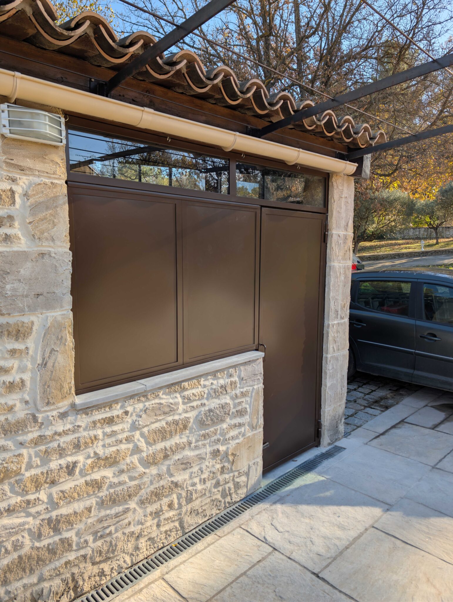 Porte en acier thermolaqué et imposte vitrée installées pour fermer une cuisine d’été à Fuveau