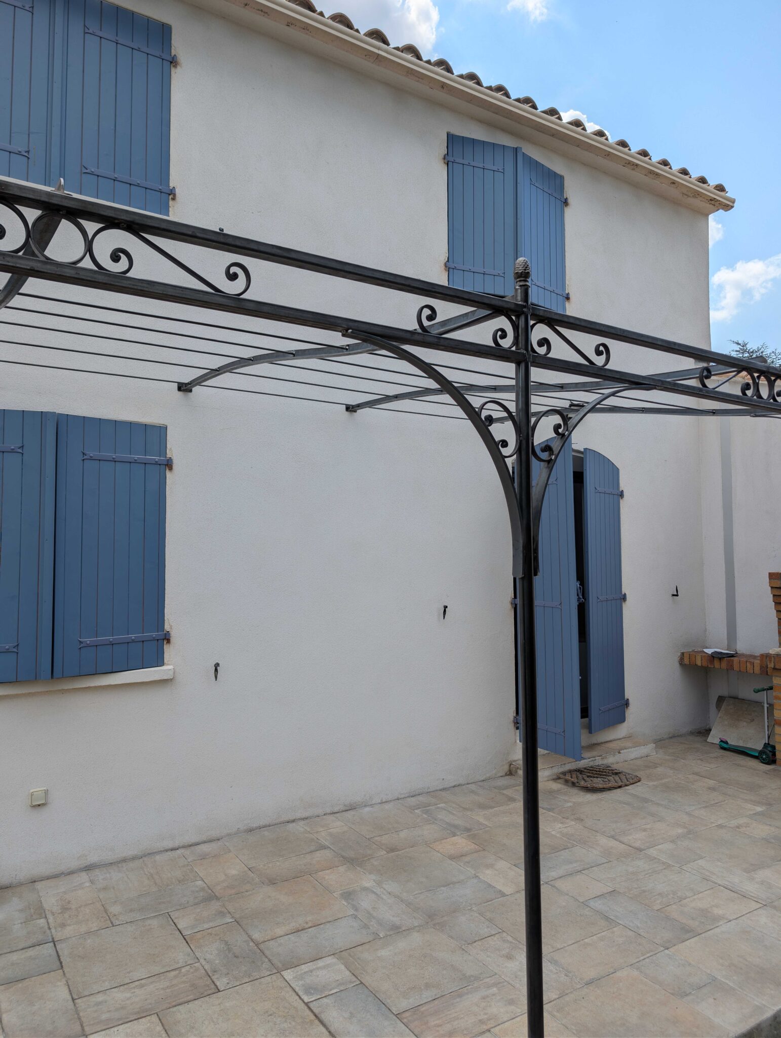 Pergola en fer forgé sur mesure en acier brut avec chapeau de gendarme et volutes décoratives à Trets